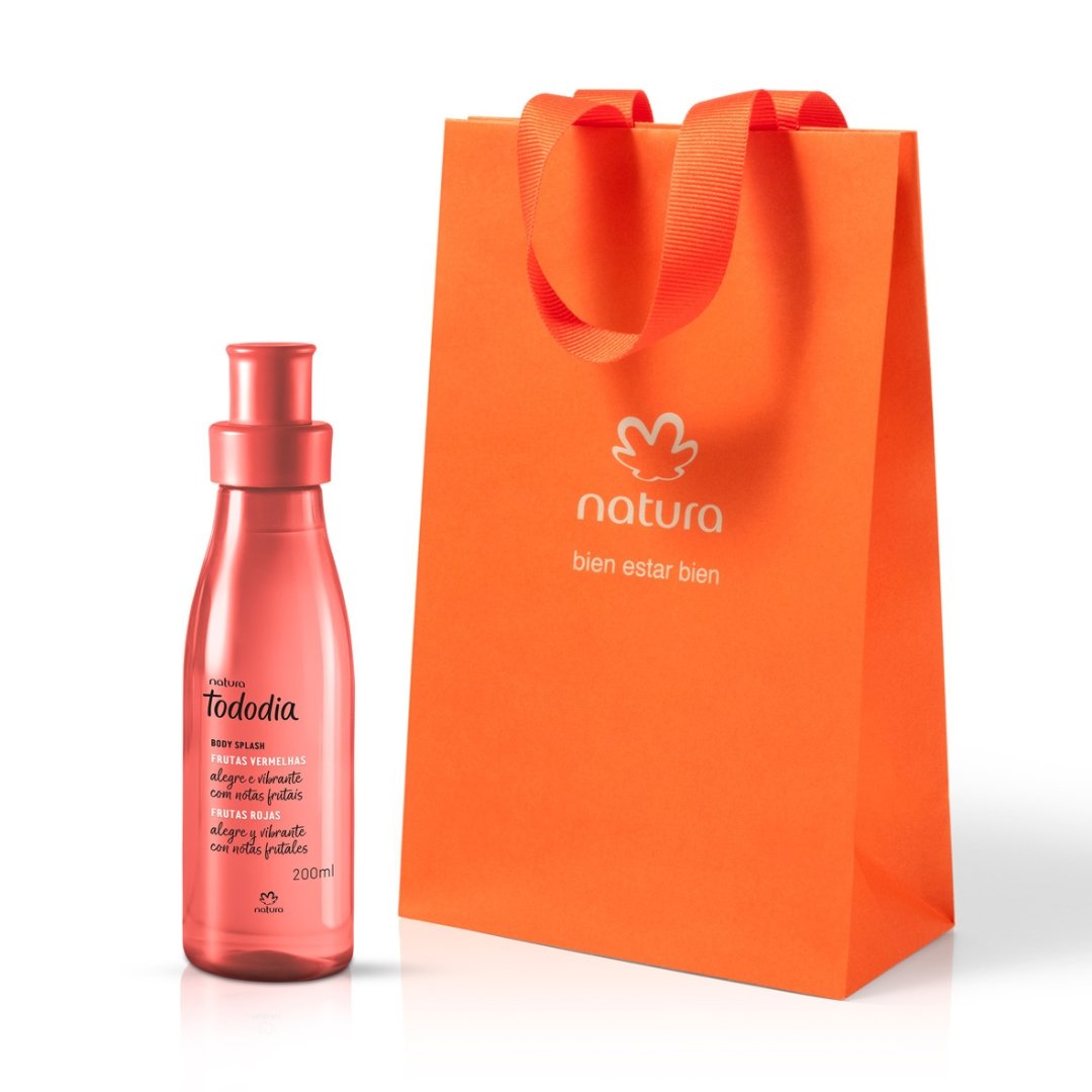 Botella de Body Splash Tododia Frutas Rojas, es roja y transparente (200ml), junto a la bolsa de regalo naranja de la marca.