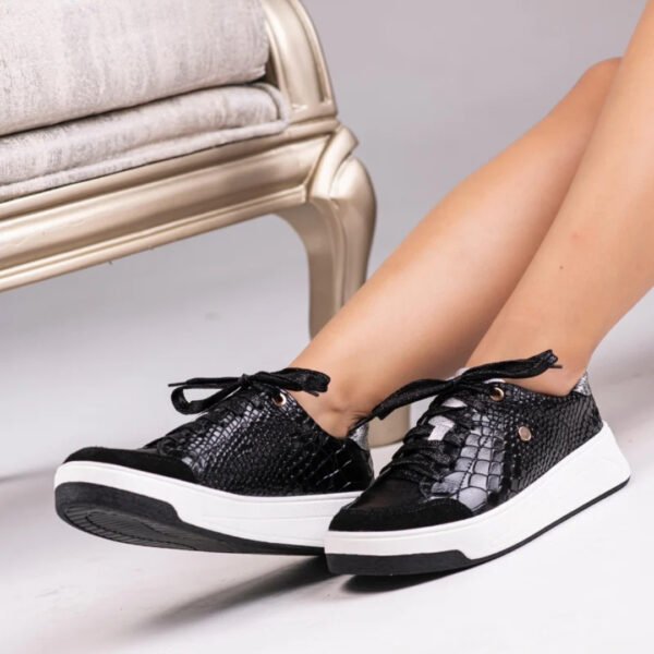 Tenis casuales de cuero negros (modelo Mamba) con diseño de franjas blancas en el lateral y suela blanca, mostrados de frente.