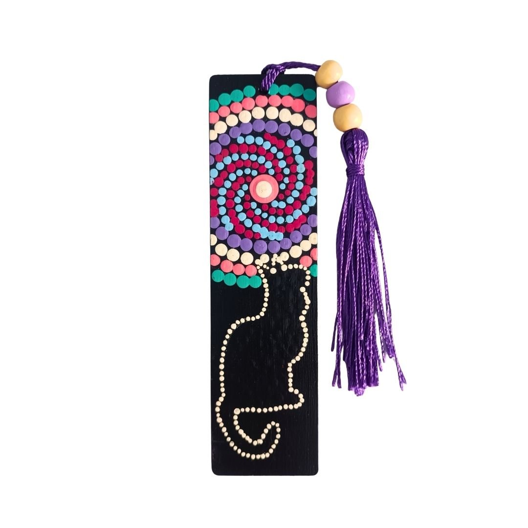 Separador de libros de madera negra con diseño de gato y un mandala en espiral, y una borla de hilo morado oscuro atada con cuentas de madera.