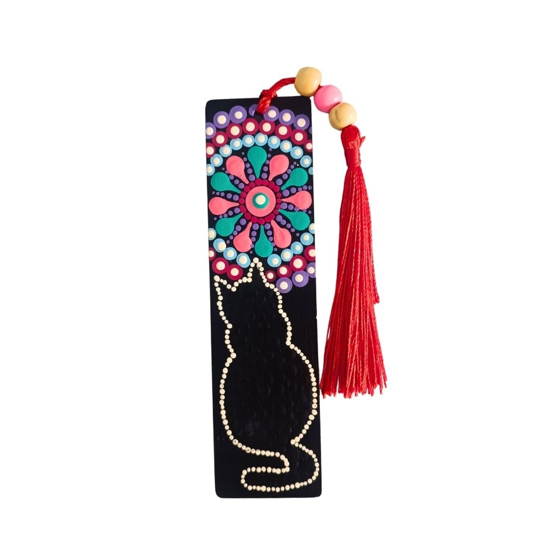 Separador de libros de madera negra con diseño de gato y mandala, y una borla de hilo rojo brillante atada con cuentas de madera.