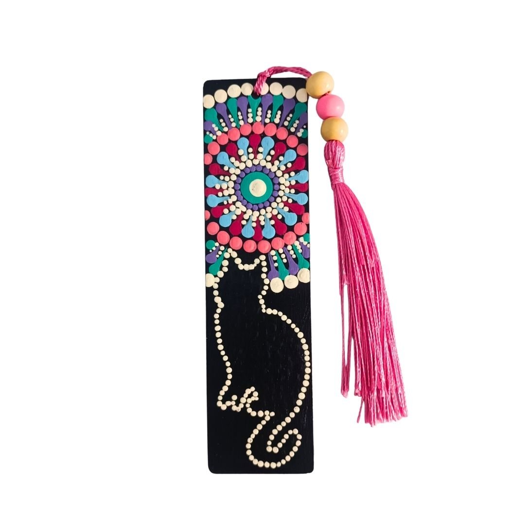 Separador de libros de madera negra con diseño de gato y mandala en colores vivos, y una borla de hilo rosa intenso atada con cuentas de madera.