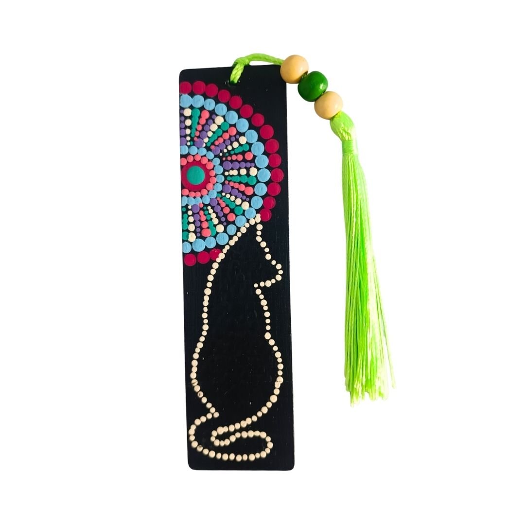 Separador de libros de madera negra con diseño de gato delineado y mandala colorido, y una borla de hilo verde limón o verde claro atada con cuentas de madera.