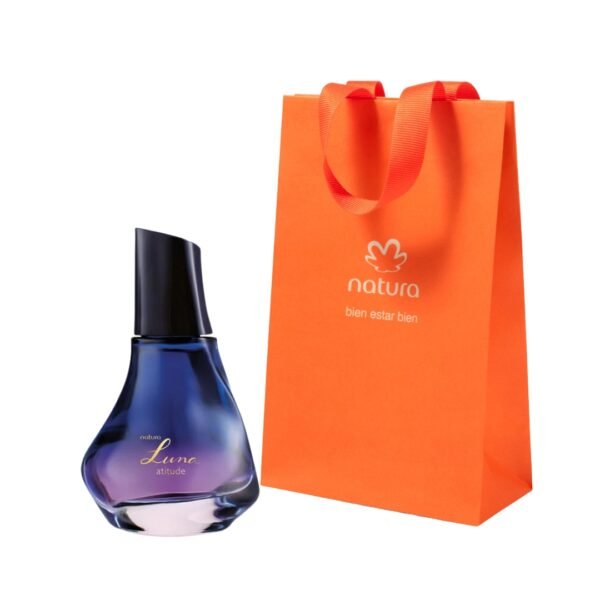 Perfume femenino Natura Luna Atitude. La imagen muestra el frasco de cristal con un diseño asimétrico y elegante, con un degradado que va desde un azul profundo en la parte superior hasta tonos violetas y rosados en la base. El frasco tiene una tapa negra estilizada y aparece junto a la bolsa de regalo naranja oficial de Natura.