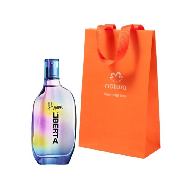 Botella de perfume Natura Humor Liberta con un diseño holográfico y multicolor que destella tonos amarillos, morados y azules, junto a una bolsa de regalo de papel color naranja con el logotipo de Natura.