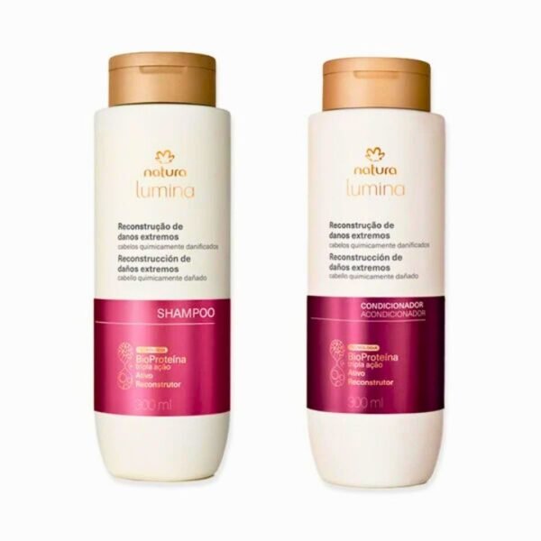 En la imagen se muestran dos botellas de la línea Natura Lumina para reconstrucción de daños extremos. La botella de la izquierda es el shampoo y la de la derecha es el acondicionador, ambas con empaque de color crema, tapa dorada y una banda inferior de color fucsia que destaca la tecnología de BioProteína de triple acción. Cada envase contiene 300 ml de producto.